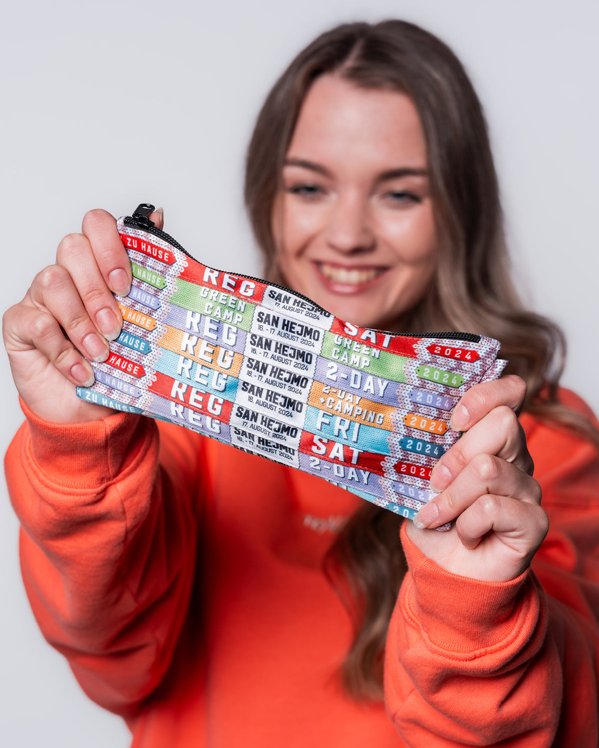 Eine kleine Tasche hergestellt aus Festivalbändchen aus dem Jahr 2024. Sie hat einen schwarzen Reißverschluss und ist im Format 16:9 geschnitten.