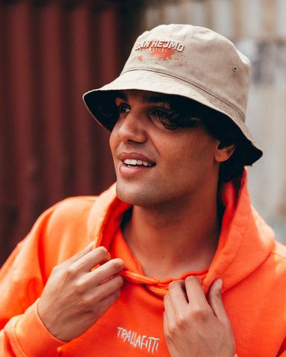 Der wendbare Bucket Hat mit der beigefarbenen Seite nach außen. Getragen wird er von einem jungen Mann.