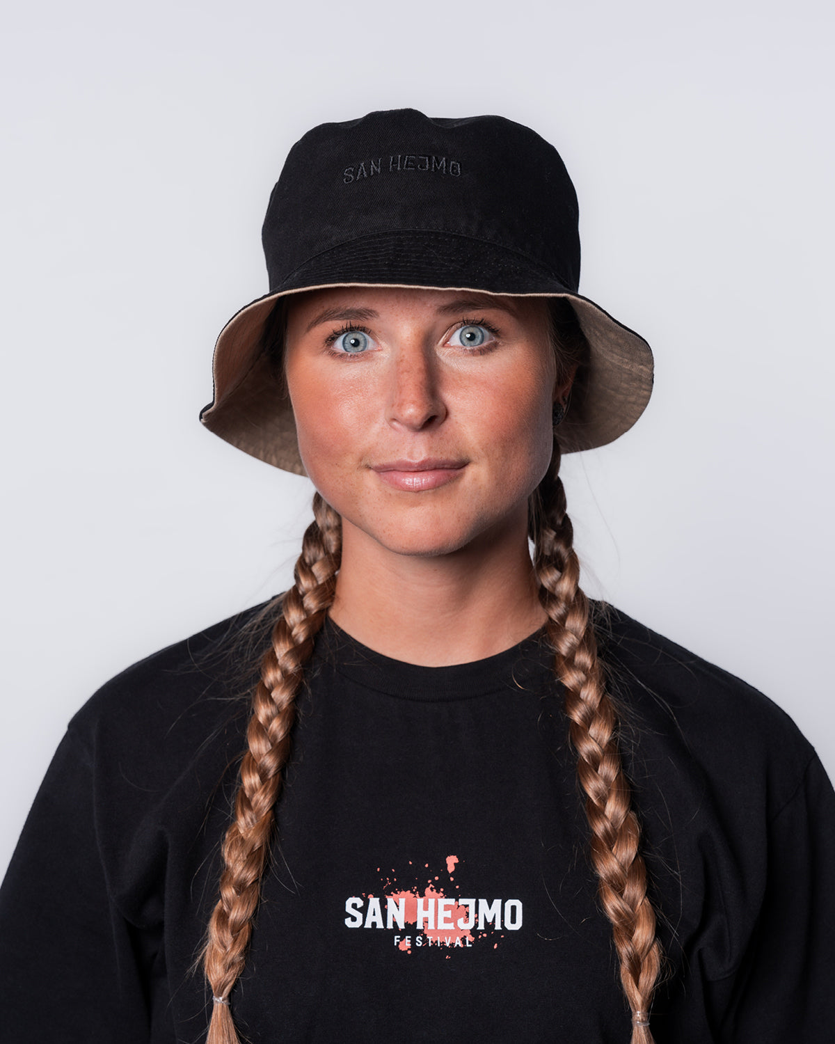 Der wendbare Bucket Hat mit der schwarzen Seite nach außen. Getragen wird er von einer jungen Frau. Der mittige schwarze Stick "San Hejmo" ist sichtbar.