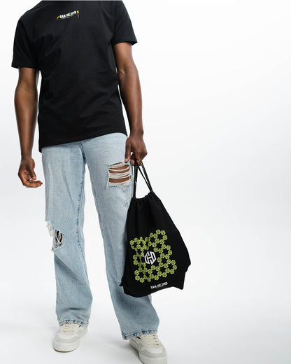 Ein schwarzer sportlicher Beutel mit dem in Bienenwaben angeordneten San Hejmo Logo in Mint. Mittig ist das San Hejmo in Weiß abgebildet. Ein Mann trägt ihn an beiden Bändern in der Hand.