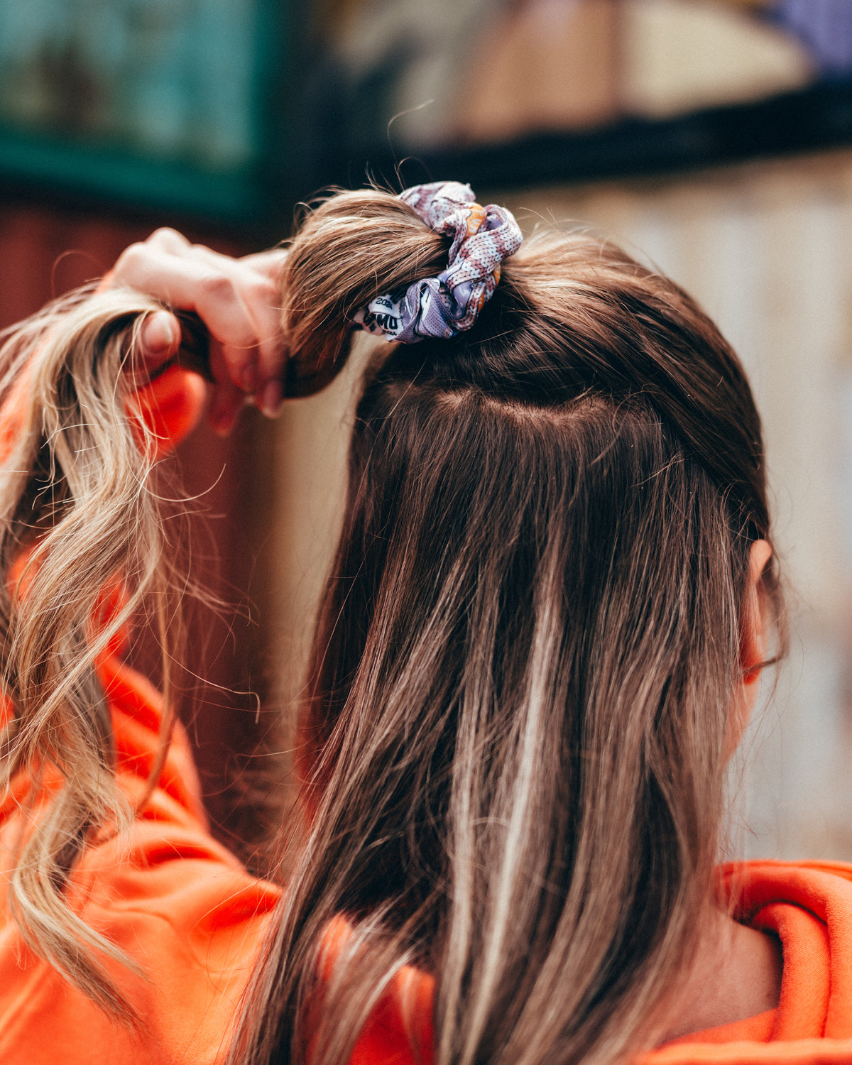 Der Scrunchie aus der Upcycling-Kollektion in einem halben Zopf. Er besteht aus Festivalbändchen aus dem Jahr 2024.