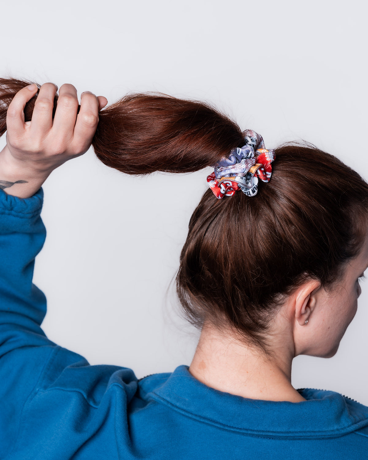 Der Scrunchie aus der Upcycling-Kollektion in einem Zopf gebunden. Er besteht aus Festivalbändchen aus dem Jahr 2024.